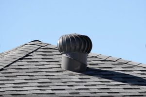 photo of an asphalt shingle roof with a turbine vent and blue sky in the background