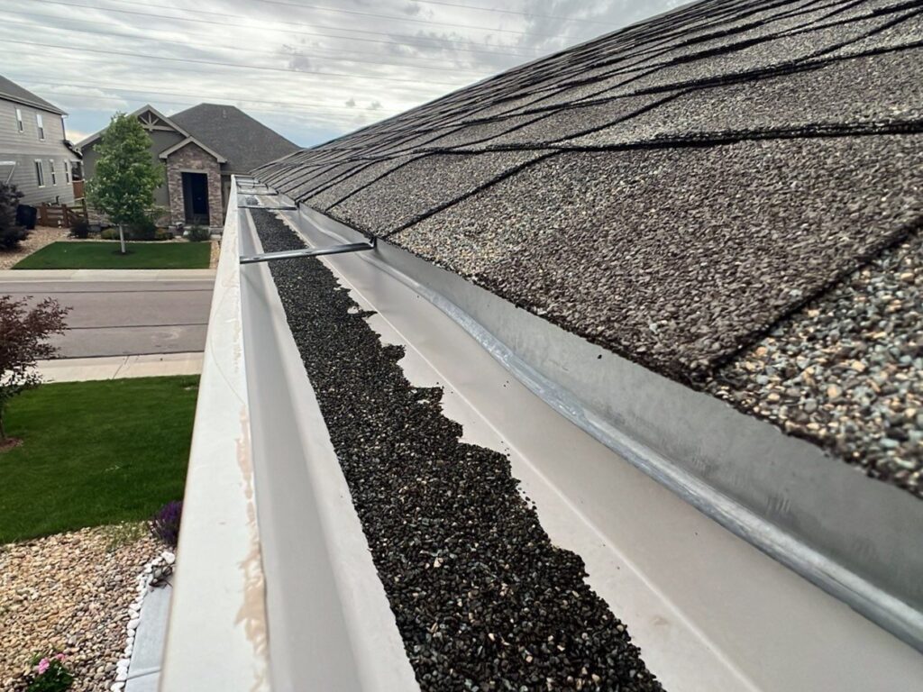 roof granules filling up gutters on a home after a hail storm the caused hail damage to the shingles