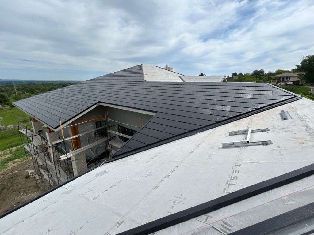 overhead image of a roof where contractors are installing solar tiles for roof replacement project