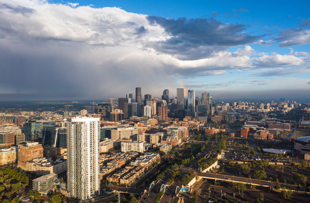 aerial view of the city of Denver Colorado with dar storm clouds coming into view and a rainbow at the edge of the storm with possible hail damage from the storm