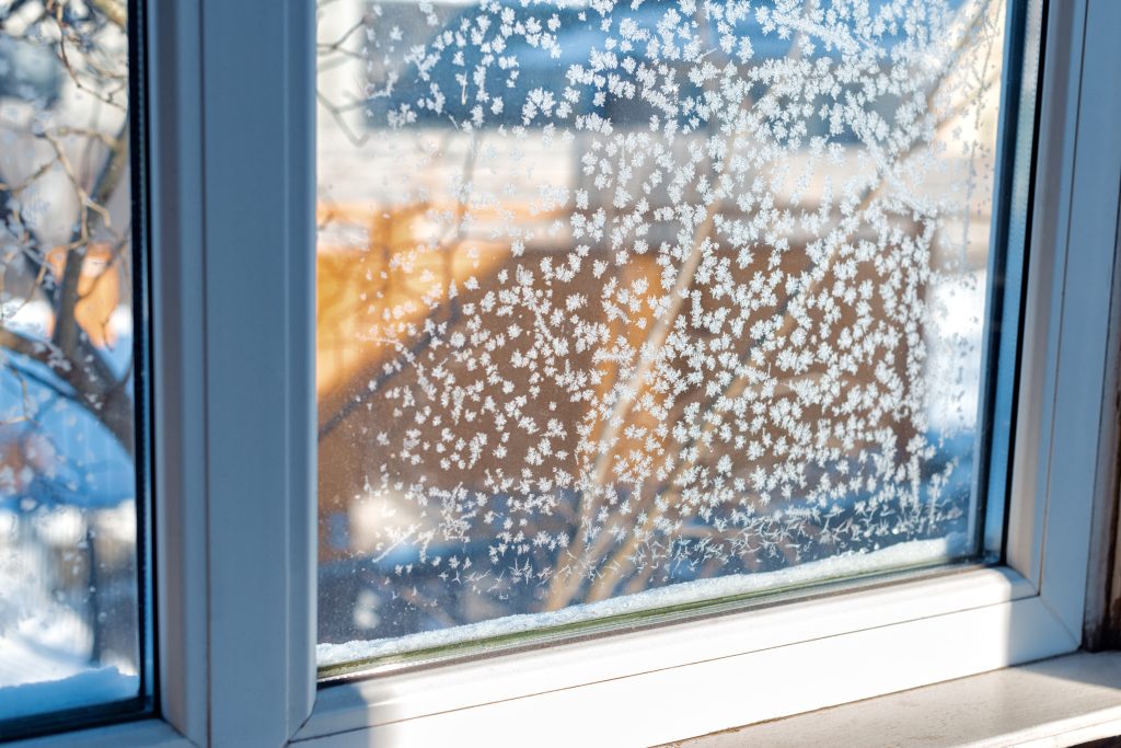 Ice pattern on winter glass from condensation caused by drafty windows in the winter.
