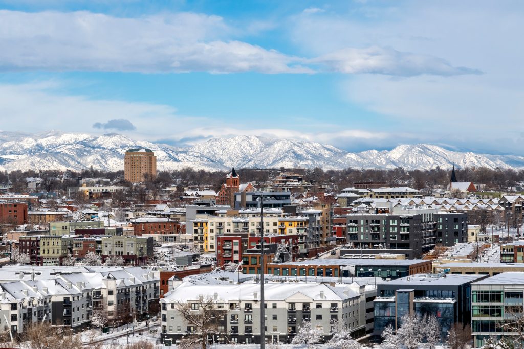 overhead view of the city of Denver after snow storm. residential and commercial roofing covered in snow with mountains in the background
